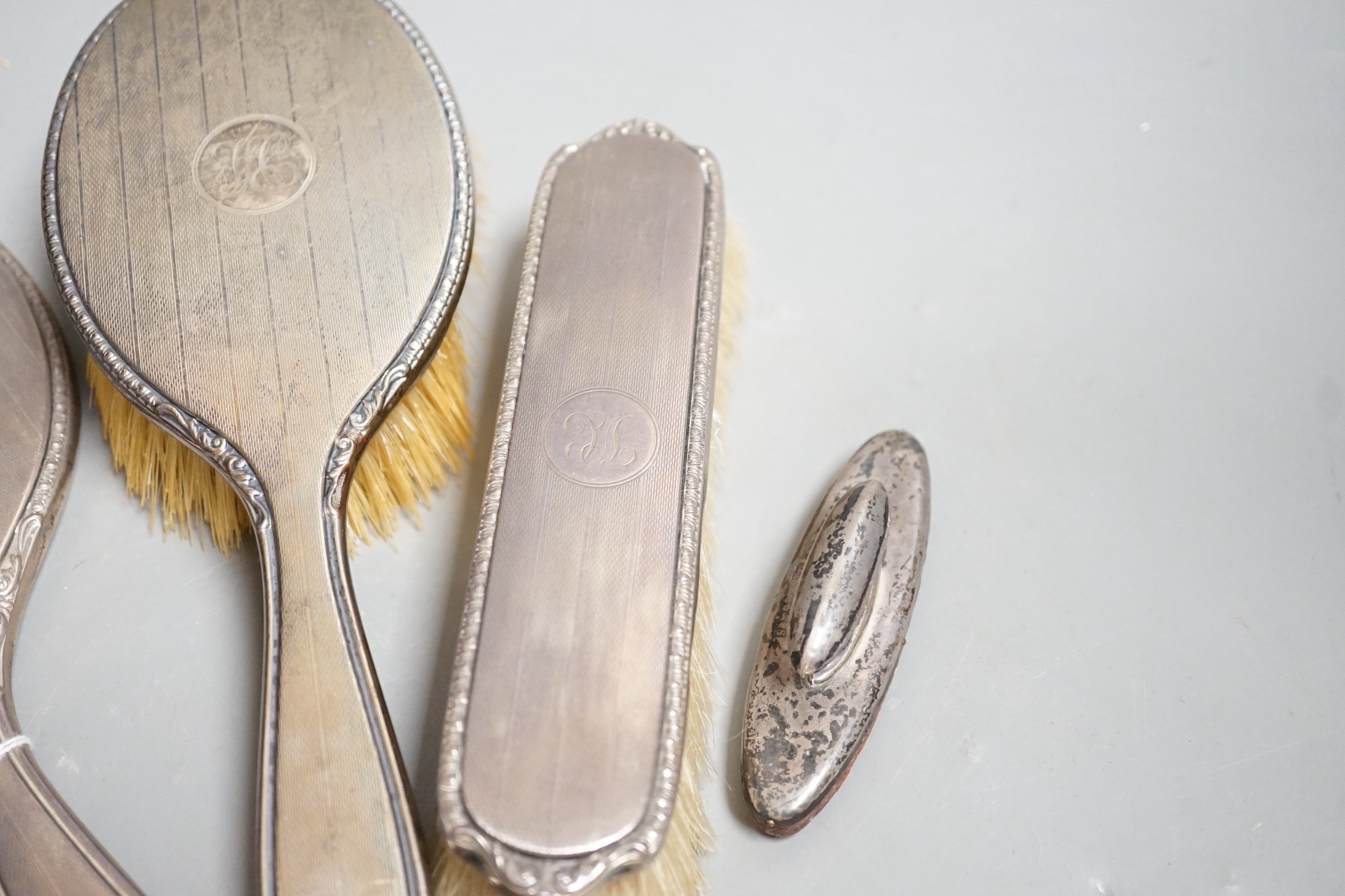 A George V silver mounted hand mirror and similar hair and clothes brush, Adie Bros. Birmingham, 1925 and a silver mounted nail buffer.